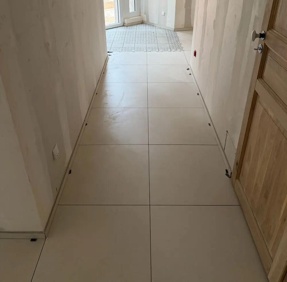 Couloir en grand format beige menant à un tapis de carreaux à motif géométrique