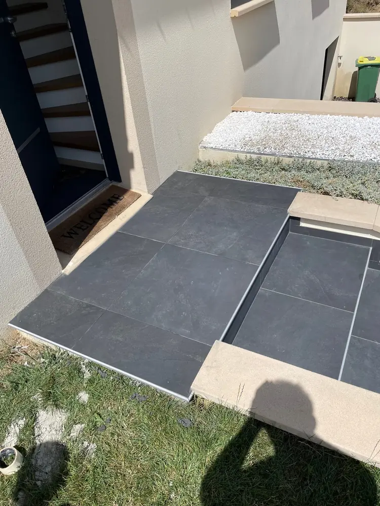 Palier d'entrée en grandes dalles anthracite effet ardoise devant une porte de maison