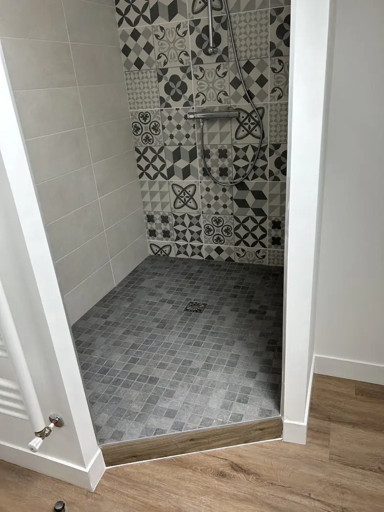 Douche à l'italienne avec mur en carreaux de ciment noir et blanc et sol en mosaïque grise