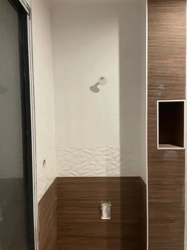 Douche en faïence blanche à relief avec colonne en carreaux effet bois strié et niche murale