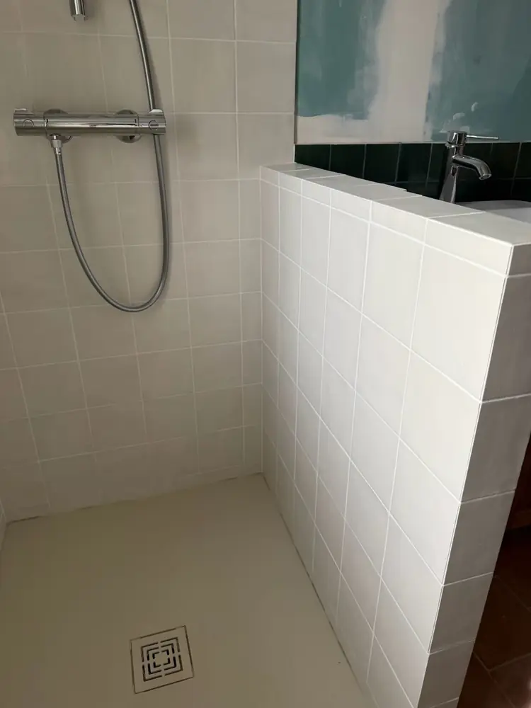 Douche avec muret carrelé en faïence blanche et receveur à grille carrée