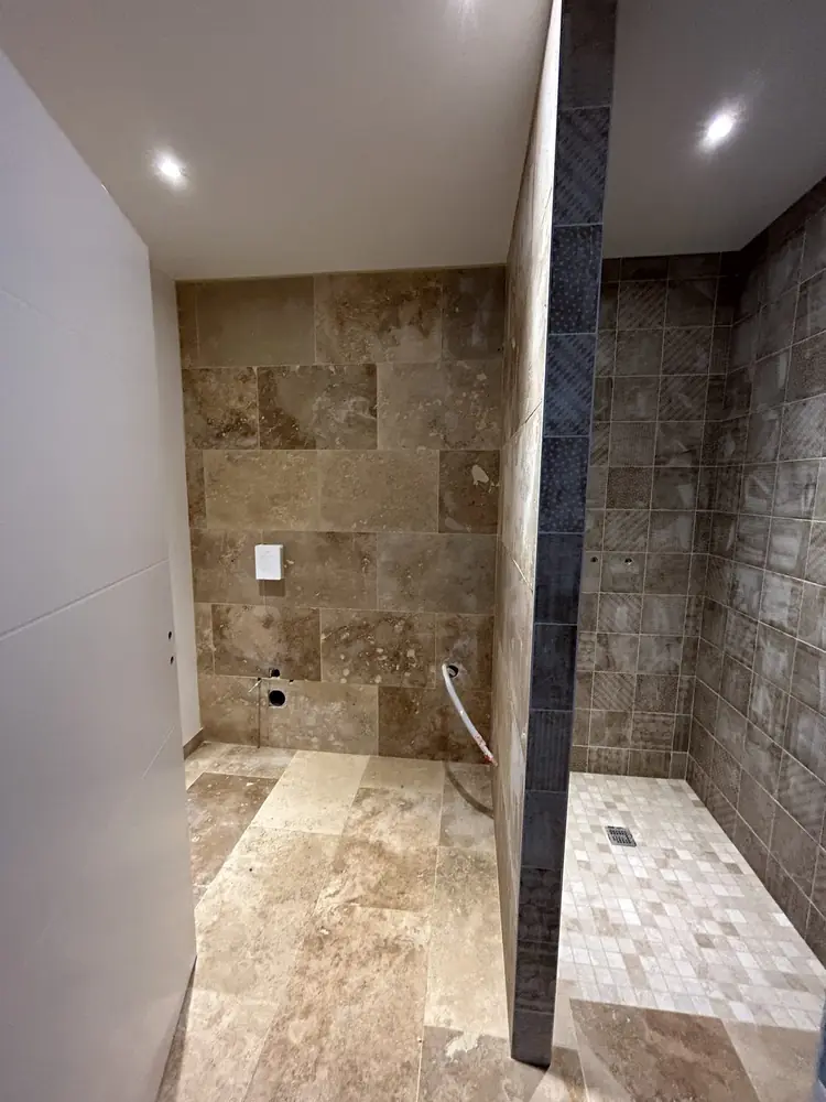 Salle d'eau avec mur en travertin et douche à l'italienne en carreaux effet pierre vieillie