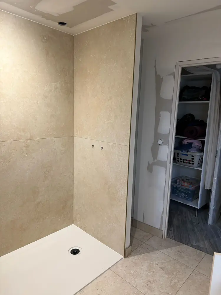 Douche avec receveur extra-plat et murs en carrelage grand format effet pierre beige