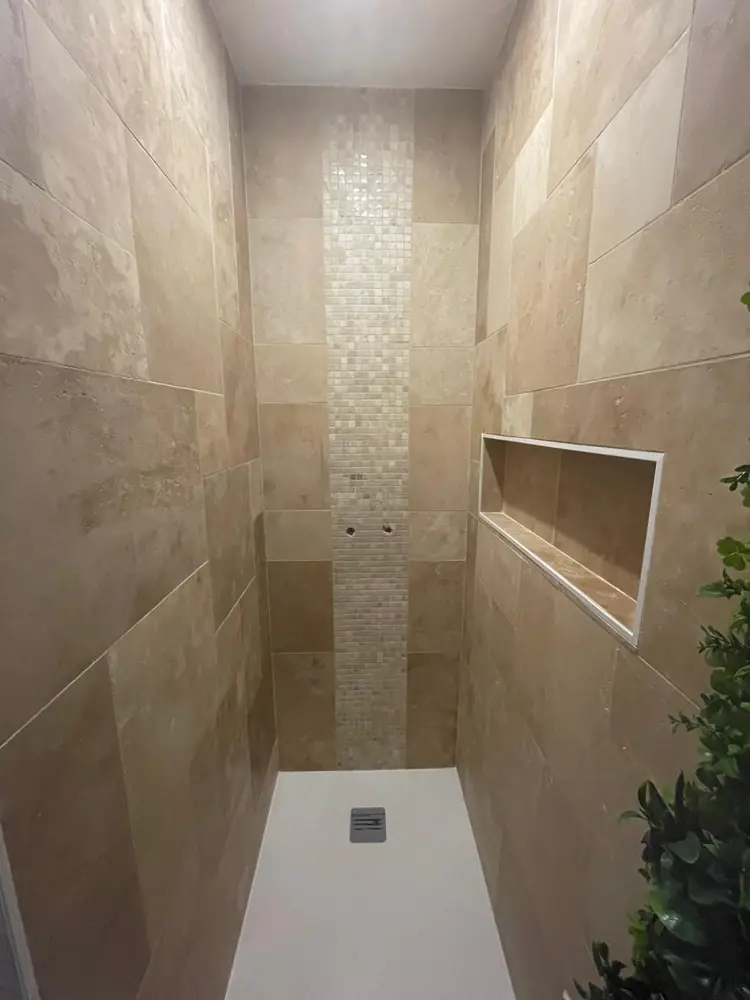 Douche en travertin avec bande verticale en mosaïque, niche latérale et receveur blanc