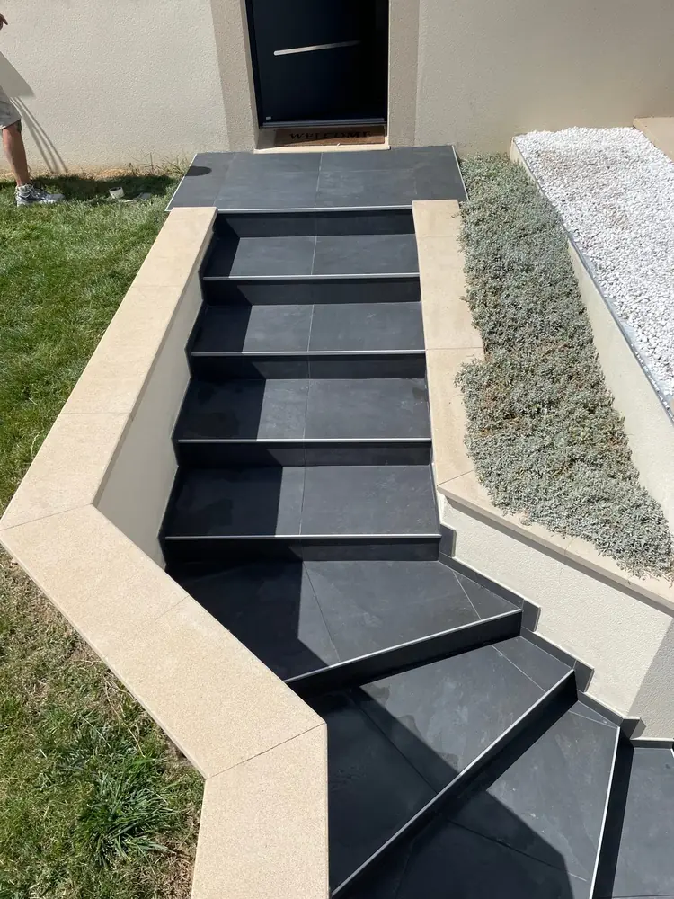 Escalier extérieur tournant en grès anthracite montant vers une porte d'entrée, près de Chartres