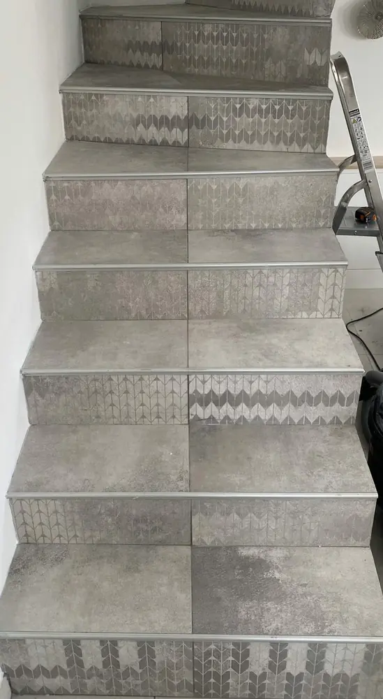 Escalier intérieur carrelé en grès gris avec contremarches décorées et nez de marche alu