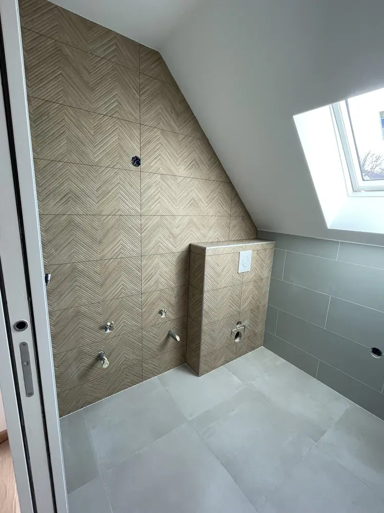 Mur sous rampant en carreaux chevron effet bois et coffrage de WC carrelé dans une salle d'eau