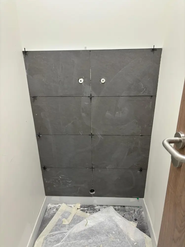 Mur de WC en grands carreaux noirs effet ardoise, croisillons de pose encore en place