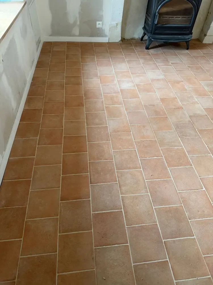 Carrelage rectangulaire aspect terre cuite dans une pièce avec poêle à bois