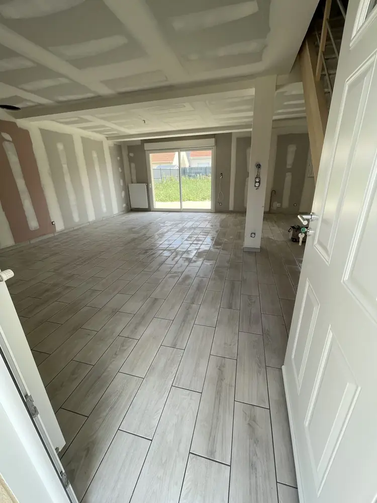 Carrelage imitation parquet gris clair posé dans le grand séjour d'une maison neuve