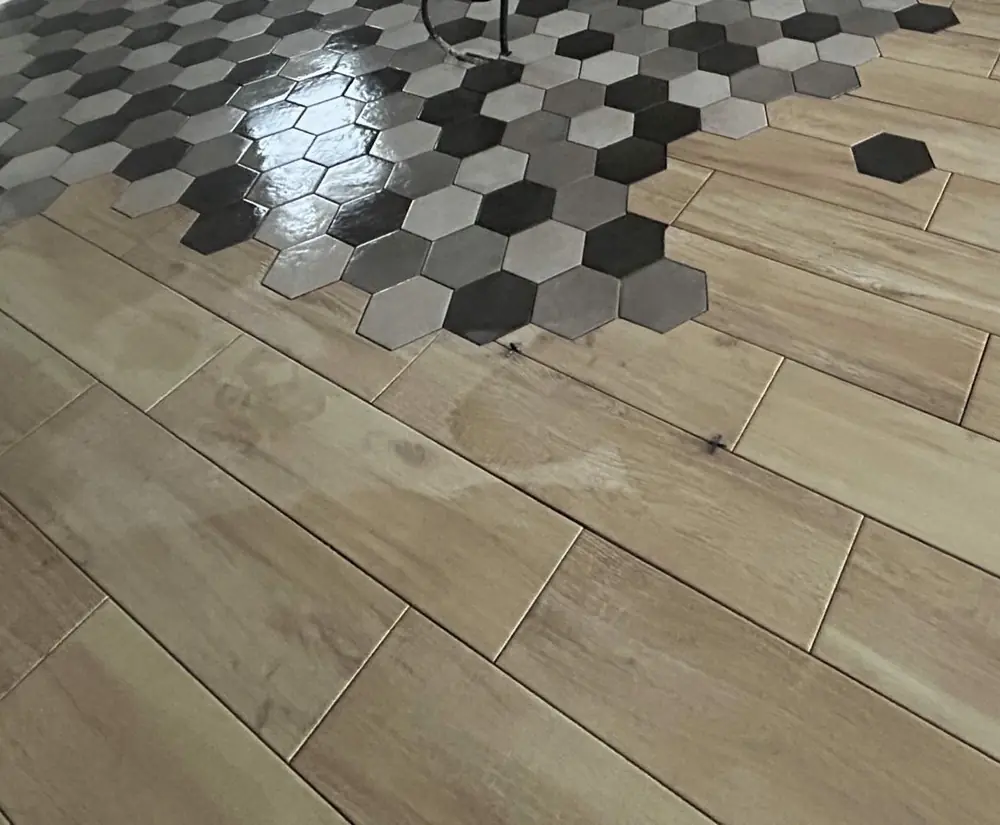 Raccord en dégradé entre carreaux hexagonaux noirs et gris et carrelage imitation bois