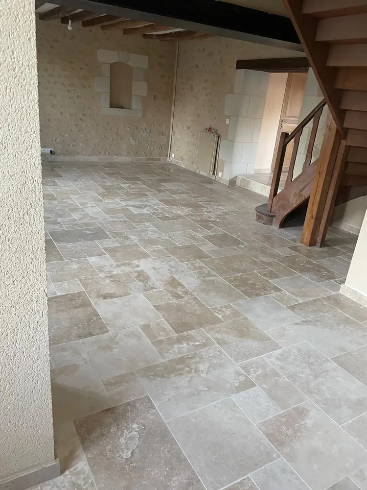 Séjour en travertin opus beige avec escalier en bois et murs en pierre, près de Chartres