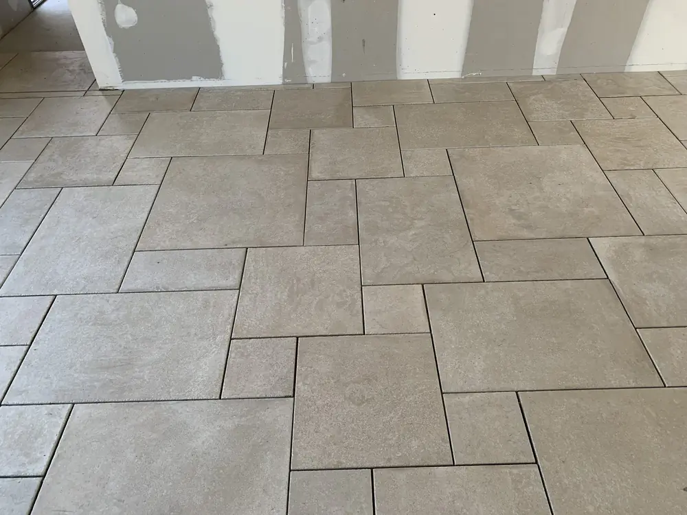 Sol en grès effet pierre gris clair posé en opus multiformat dans une pièce en travaux