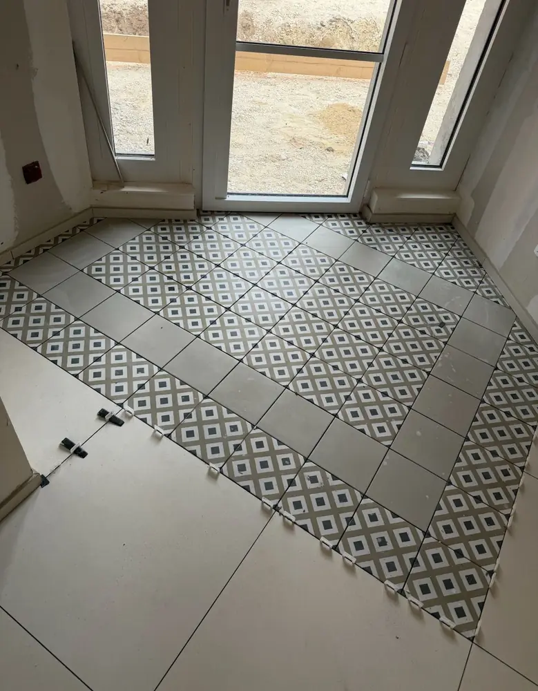 Tapis d'entrée en carreaux à motif géométrique encadré dans un sol en grand format beige
