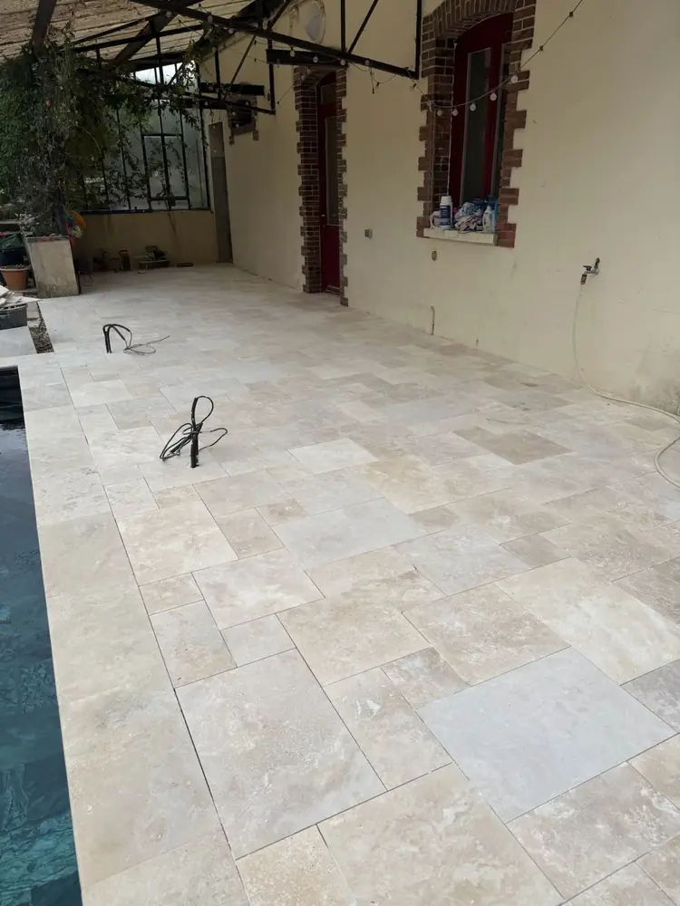 Terrasse en travertin opus romain longeant un bassin étroit sous verrière