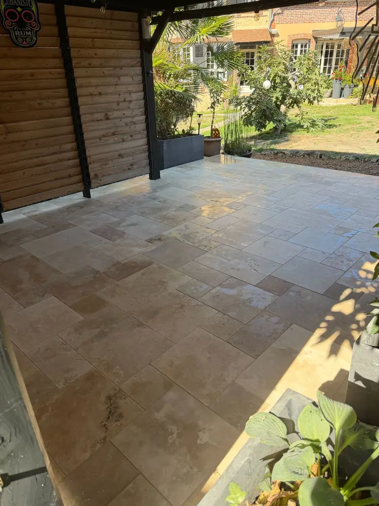 Terrasse en travertin mouillé sous carport, vue vers le jardin