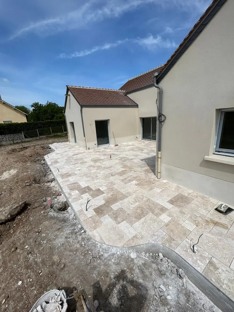 Terrasse en travertin opus à bordure courbe autour d'une maison neuve, près de Chartres