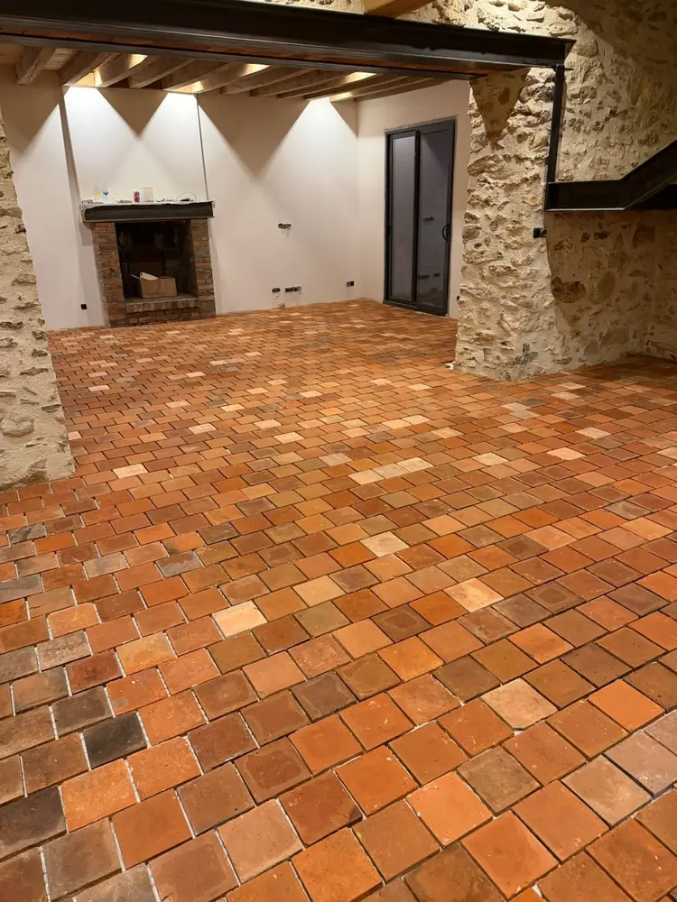 Sol en tomettes anciennes en terre cuite nuancée dans une maison en pierre avec poutres et cheminée, Eure-et-Loir