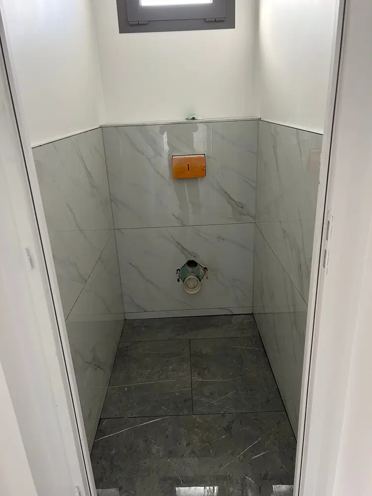 WC avec soubassement en grands carreaux effet marbre blanc et sol effet marbre gris