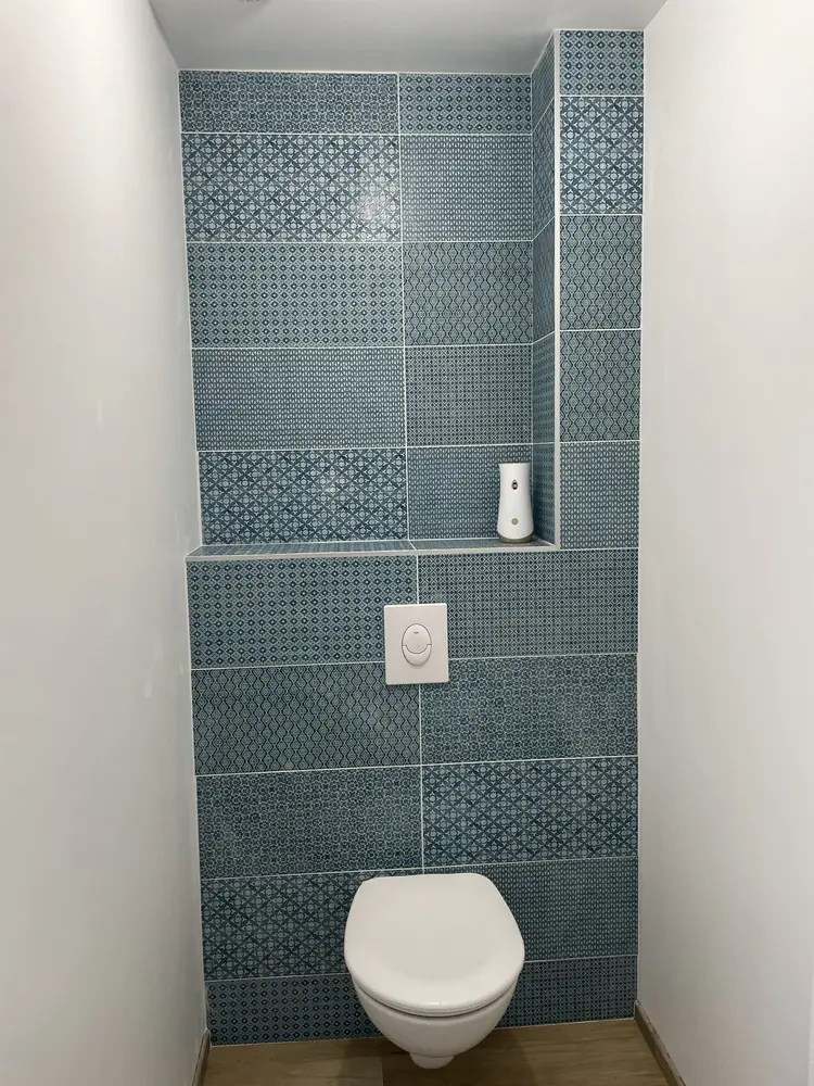 WC suspendu avec mur en faïence bleue à motifs et tablette carrelée